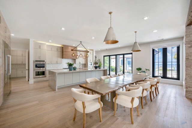 dining space with light hardwood / wood-style floors, sink, a wealth of natural light, and french doors