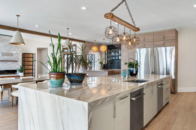 kitchen with white cabinets, a large island with sink, light stone countertops, and hanging light fixtures