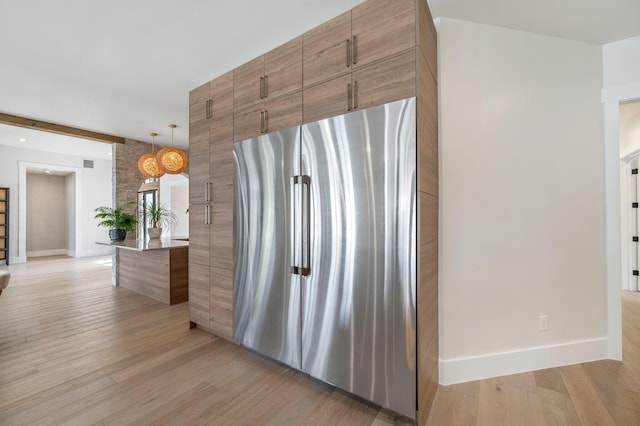 kitchen featuring stainless steel fridge, pendant lighting, beamed ceiling, and light hardwood / wood-style floors