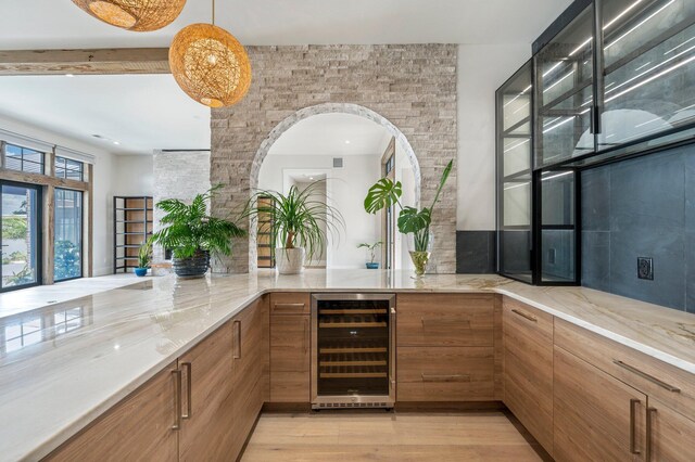 bar featuring hanging light fixtures, light wood-type flooring, and beverage cooler