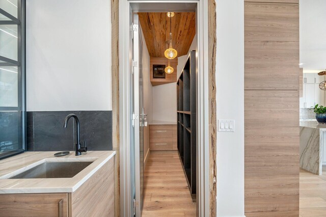 interior space featuring tasteful backsplash, sink, wooden ceiling, and light hardwood / wood-style flooring