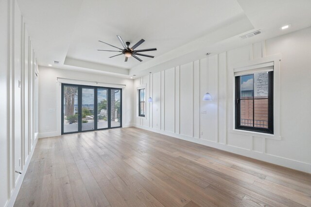 spare room featuring french doors, a tray ceiling, light hardwood / wood-style flooring, and ceiling fan