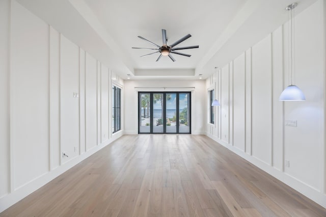 empty room featuring a tray ceiling, light hardwood / wood-style flooring, and ceiling fan