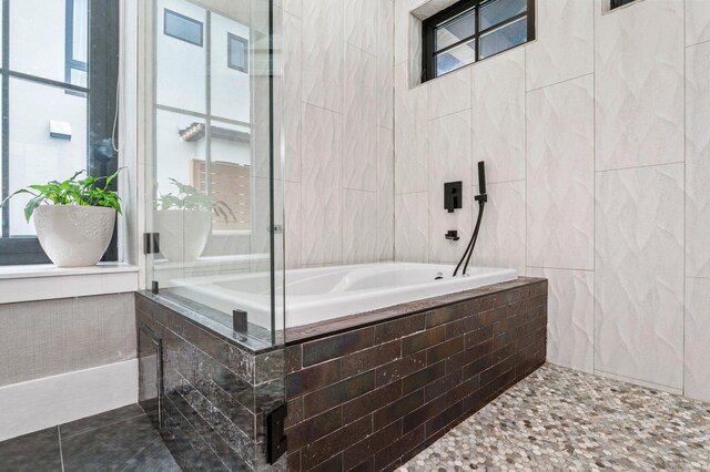 bathroom with tile patterned floors, tile walls, and tiled bath