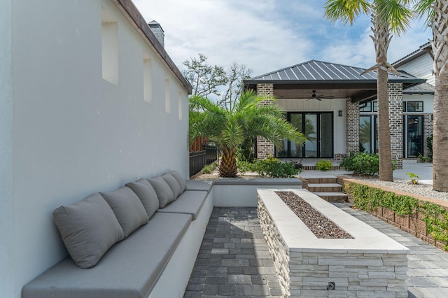 view of patio / terrace with ceiling fan and an outdoor living space with a fire pit