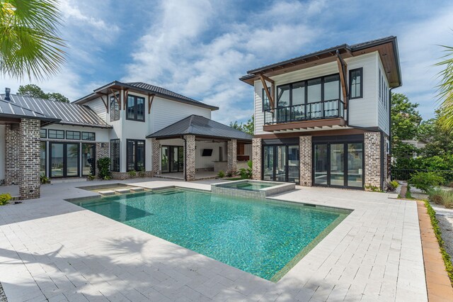 back of house featuring a pool with hot tub, a balcony, and a patio