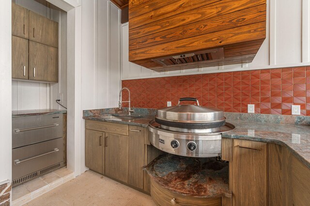 kitchen with decorative backsplash, light tile patterned floors, sink, and dark stone counters