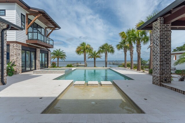 view of pool with an in ground hot tub, a water view, and a patio