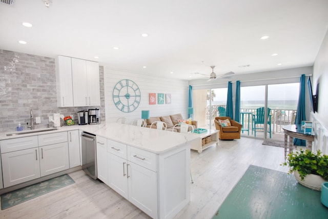 kitchen featuring kitchen peninsula, sink, white cabinets, and stainless steel dishwasher