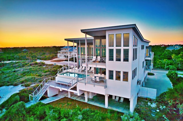 back house at dusk featuring a deck and a patio area