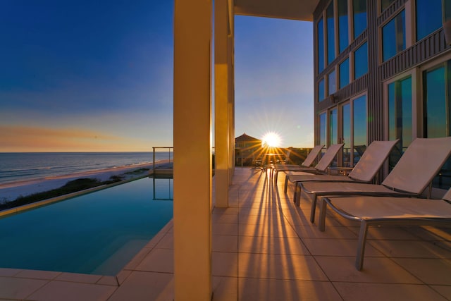 pool at dusk featuring a beach view and a water view