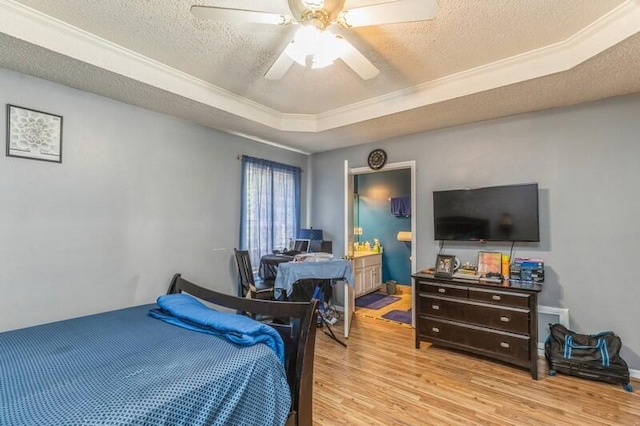 bedroom featuring ceiling fan, a tray ceiling, a textured ceiling, and light hardwood / wood-style flooring