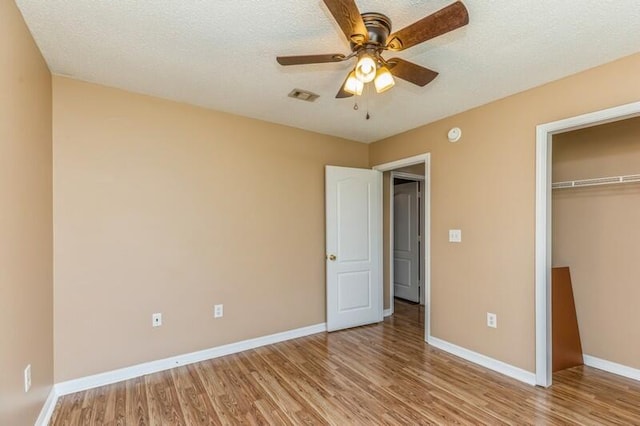 unfurnished bedroom with light wood-type flooring, a textured ceiling, a closet, and ceiling fan