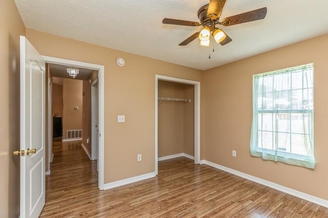 unfurnished bedroom featuring ceiling fan, multiple windows, a closet, and hardwood / wood-style floors