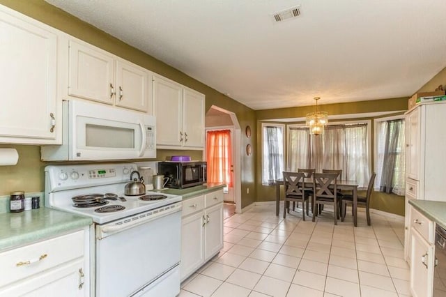 kitchen featuring white appliances, white cabinets, light tile flooring, and a chandelier