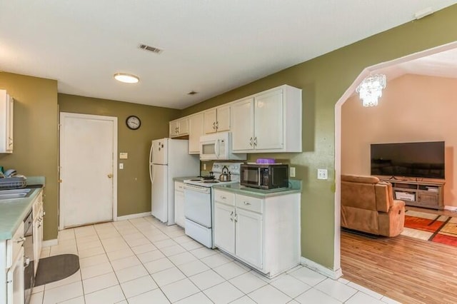 kitchen featuring sink, white cabinetry, white appliances, and light tile flooring