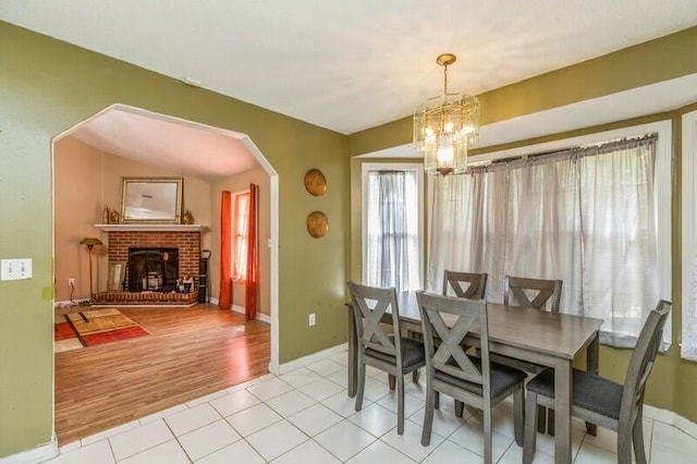 dining room featuring a chandelier, tile flooring, and a fireplace