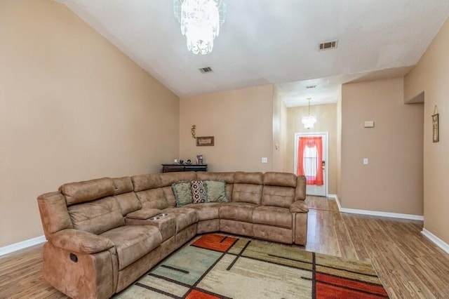 living room with hardwood / wood-style flooring, vaulted ceiling, and an inviting chandelier