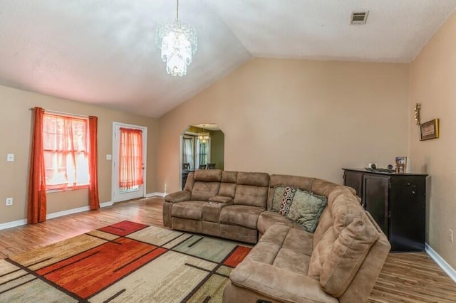 living room with hardwood / wood-style floors, a chandelier, and lofted ceiling