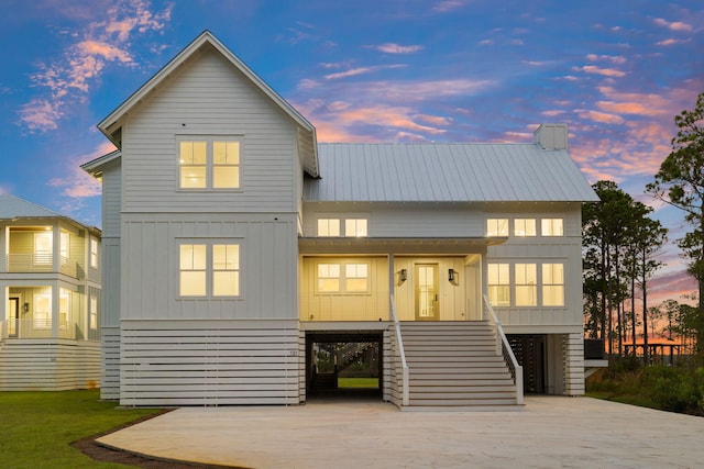 view of front of home featuring concrete driveway, stairway, board and batten siding, metal roof, and a carport