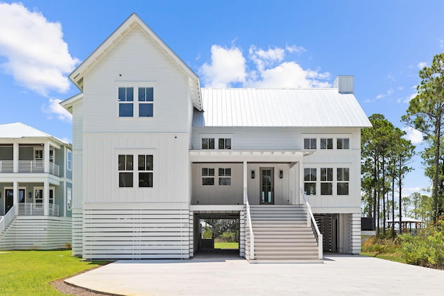 view of front of property with stairs, metal roof, board and batten siding, and driveway