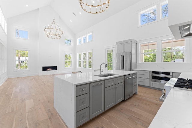 kitchen featuring a notable chandelier, appliances with stainless steel finishes, a sink, and gray cabinetry