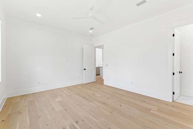 spare room featuring light wood-style flooring, visible vents, baseboards, and ornamental molding