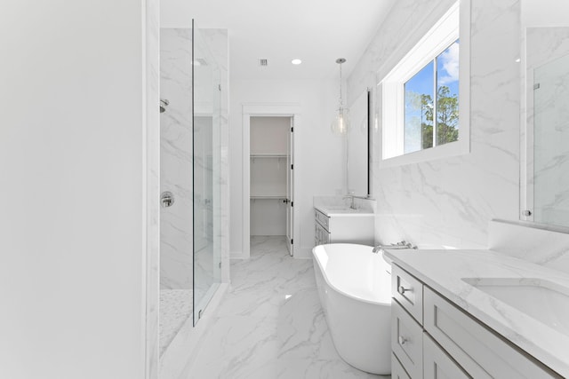 full bathroom with marble finish floor, a marble finish shower, a freestanding tub, and a sink