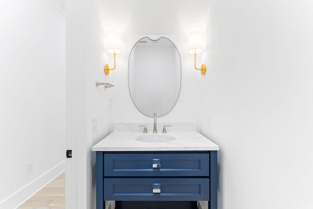 bathroom with baseboards, wood finished floors, and vanity