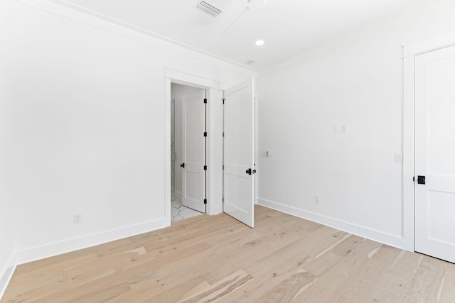 unfurnished room featuring light wood-style floors, visible vents, crown molding, and baseboards