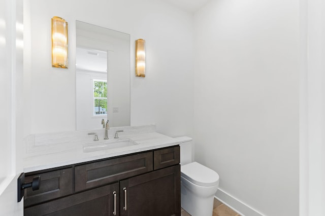 bathroom with toilet, baseboards, and vanity