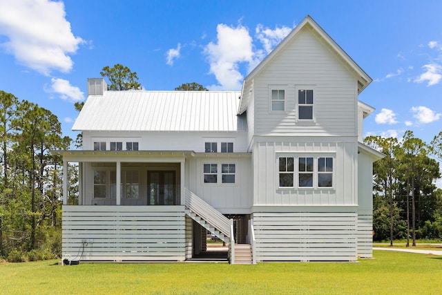 view of front facade featuring a sunroom, stairway, metal roof, a front lawn, and board and batten siding