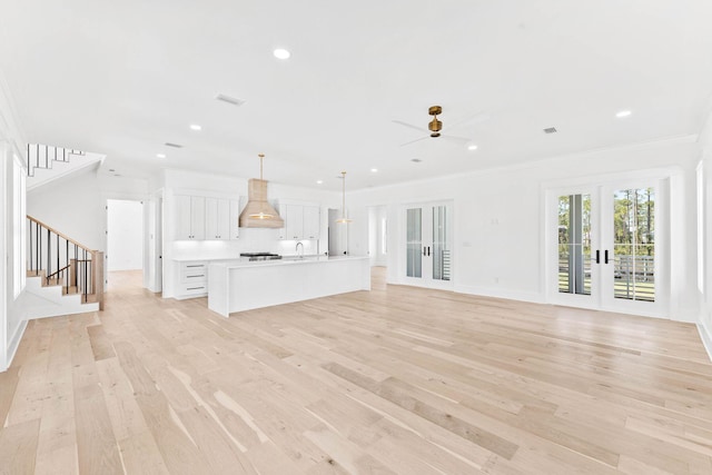 unfurnished living room with ornamental molding, french doors, light wood-type flooring, and ceiling fan