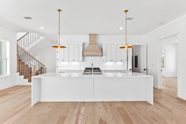 kitchen featuring pendant lighting, light wood-type flooring, and premium range hood