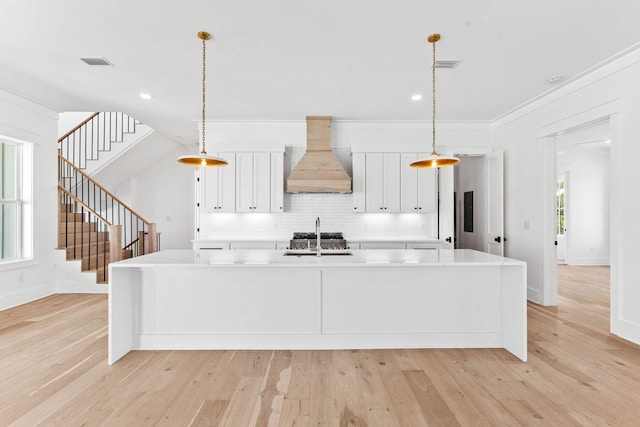 109 W Nursery Rd, Santa Rosa Beach, FL 32459 - kitchen featuring custom exhaust hood, a sink, tasteful backsplash, an island with sink, and light countertops