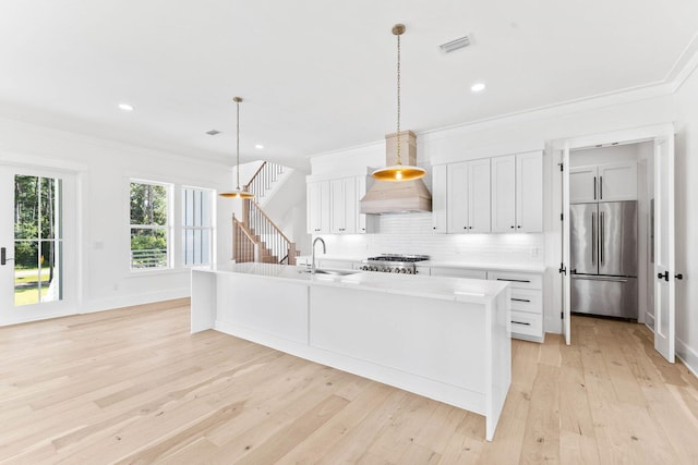 kitchen featuring backsplash, stainless steel built in fridge, and light hardwood / wood-style flooring