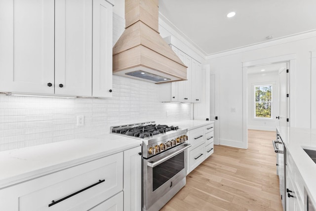 kitchen featuring white cabinetry, high end stainless steel range, crown molding, light wood-type flooring, and premium range hood