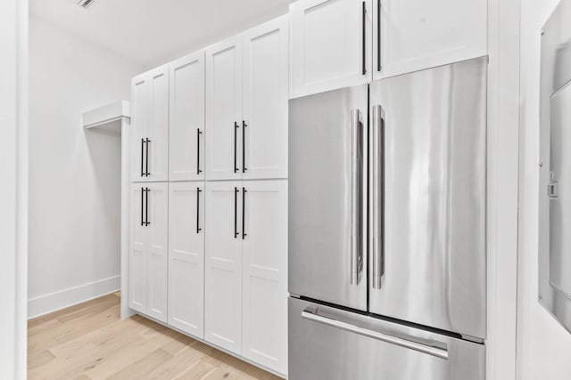 kitchen with light hardwood / wood-style flooring, stainless steel refrigerator, and white cabinetry