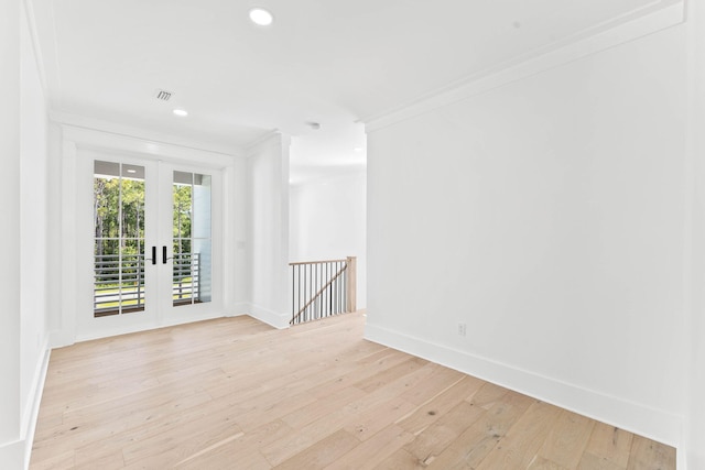 empty room featuring crown molding, french doors, and light hardwood / wood-style flooring