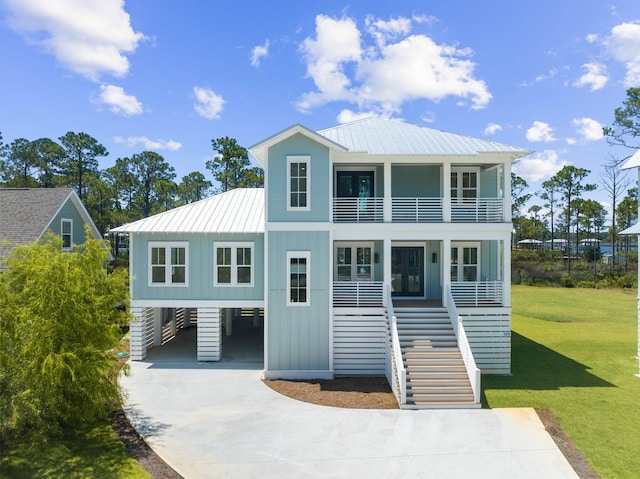 109 W Nursery Rd, Santa Rosa Beach, FL 32459 - raised beach house featuring a balcony, stairs, driveway, a front yard, and board and batten siding