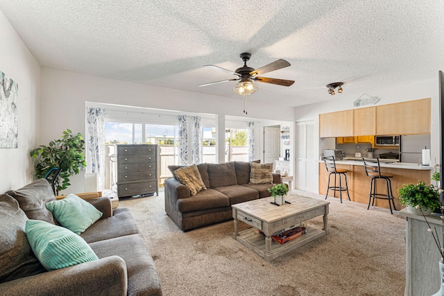 carpeted living room featuring ceiling fan and a textured ceiling