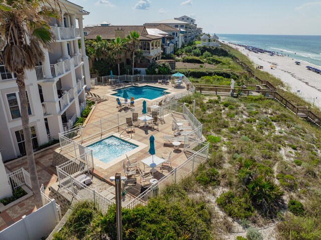 view of pool with a patio area, a water view, and a beach view