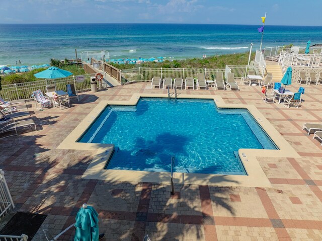 view of pool featuring a water view and a patio