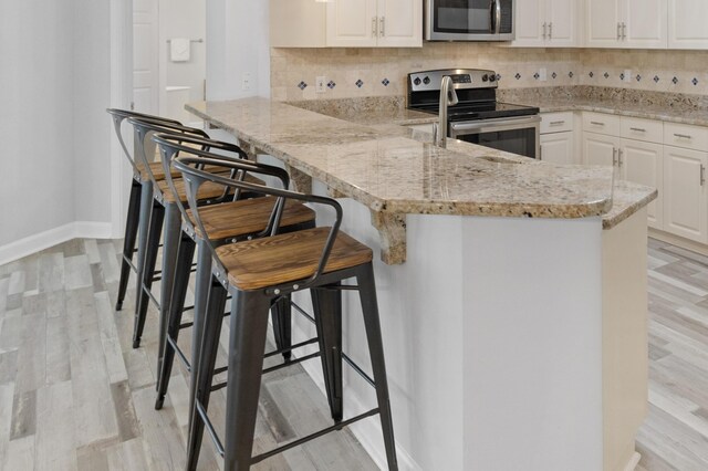 kitchen with a kitchen bar, kitchen peninsula, and stainless steel appliances