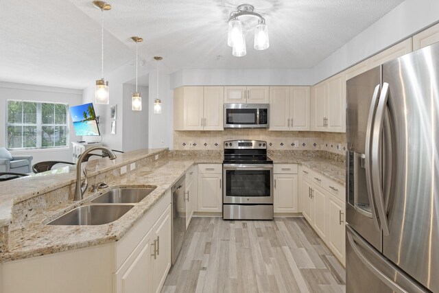 kitchen featuring appliances with stainless steel finishes, backsplash, light stone counters, sink, and pendant lighting