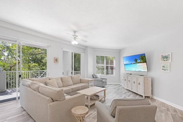 living room featuring a wealth of natural light, ceiling fan, light hardwood / wood-style floors, and a textured ceiling