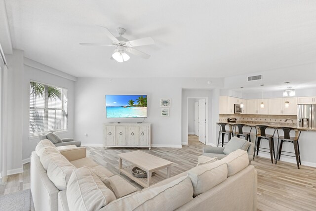 living room featuring ceiling fan and light hardwood / wood-style flooring