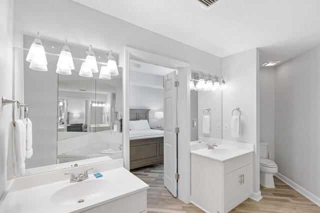 bathroom featuring vanity, toilet, wood-type flooring, and a textured ceiling