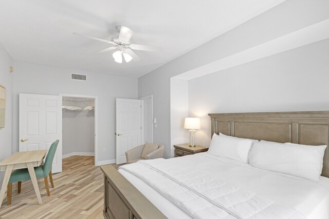 bedroom with light wood-type flooring, a closet, a spacious closet, and ceiling fan