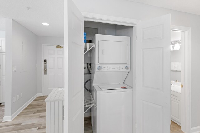 laundry area with light wood-type flooring and stacked washing maching and dryer